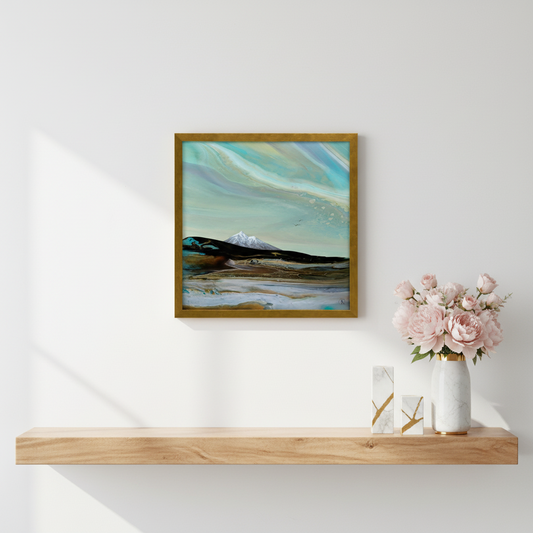 Framed artwork of a mountain landscape with a gold frame on a white wall.